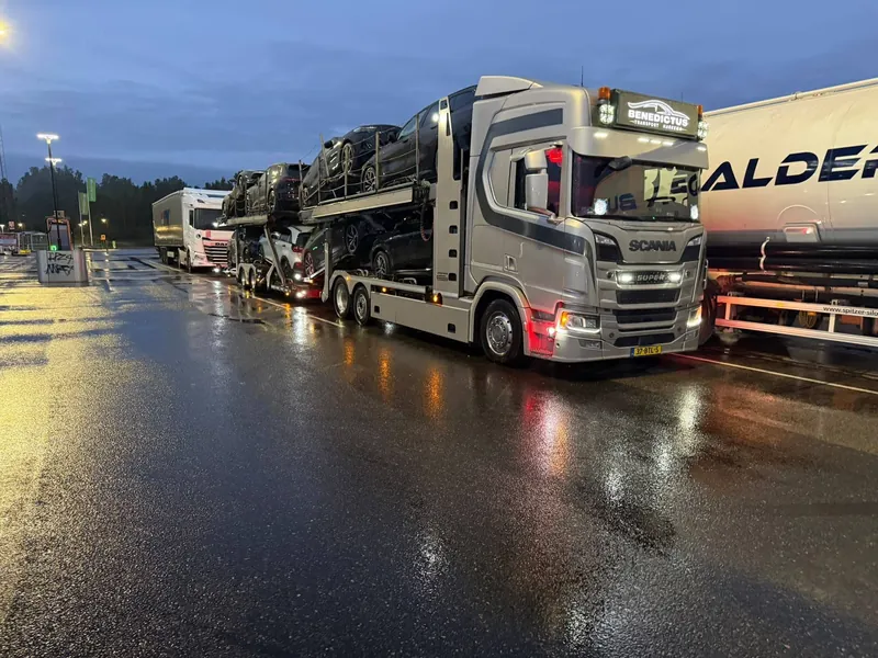 Beladen autotransporter in de avond op een natte parkeerplaats